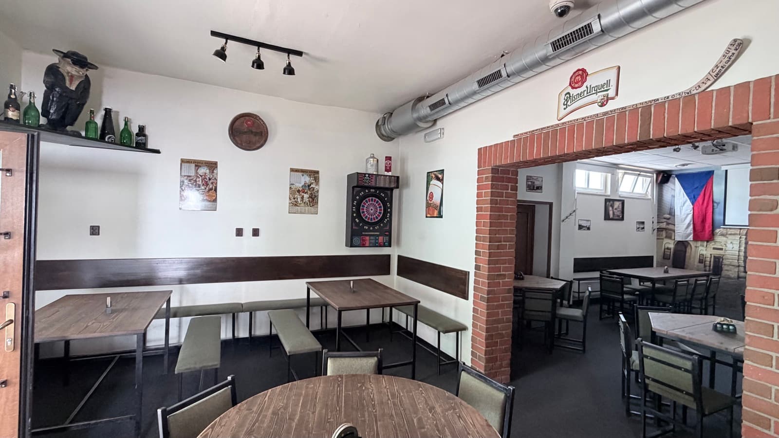 Interiér Mlýkárny — dřevěné stoly, cihlové oblouky a vlajka